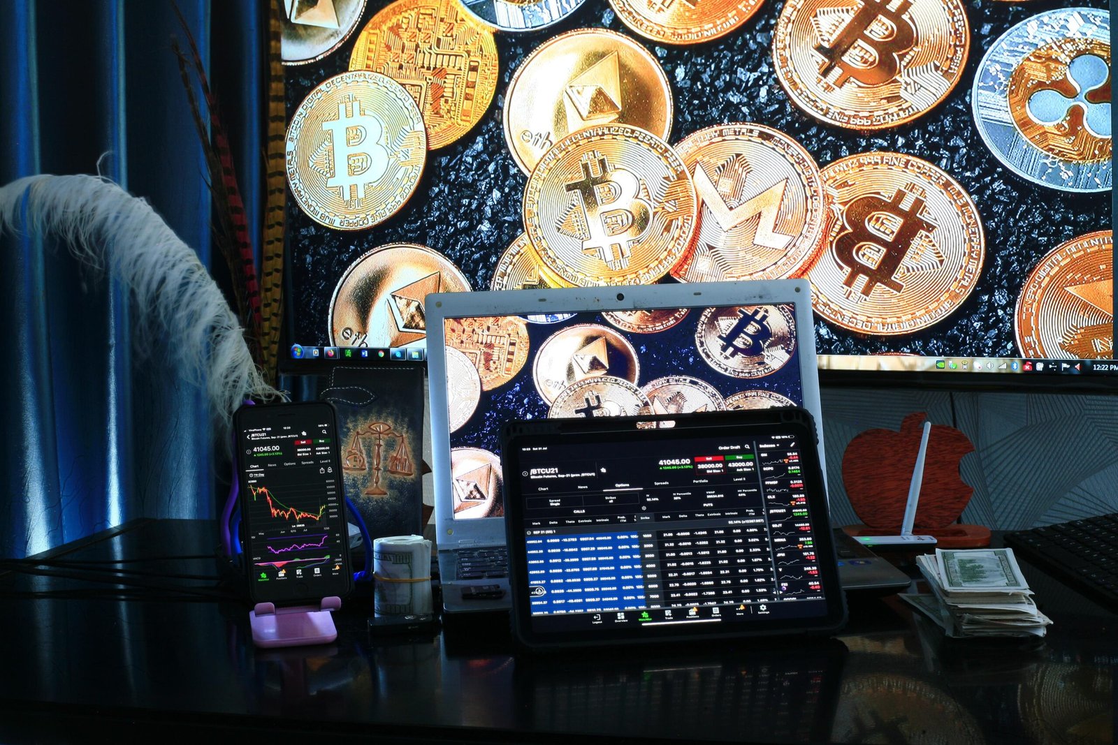 Imagem de computador em uma escrivaninha exibindo gráficos de investimentos, cifrões e criptomoedas